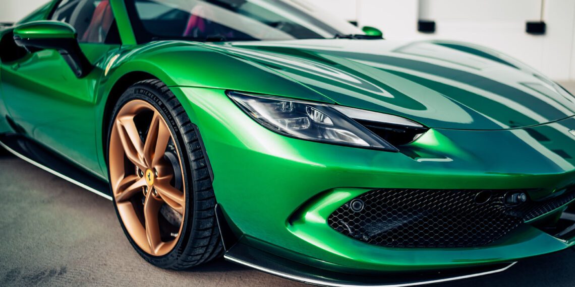 A close-up view of a shiny green Ferrari 296 GTS with gold wheels, a modern tribute parked on a concrete surface.