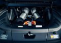 Close-up view of a Ferrari 296 GTS engine bay, showcasing modern tribute details like engine components, cables, and the iconic Ferrari logo badge at the center—an enticing look for anyone seeking a Ferrari for sale.
