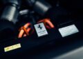 Close-up of a Ferrari 296 GTS engine compartment, featuring a metal plate with the prancing horse logo and chassis number 316053—a modern tribute to Ferrari performance, surrounded by detailed engine components and labels.