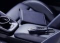 A car key and a closed notebook rest on the blue leather front passenger seat and center console of a Porsche 911.
