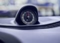 Close-up view of an analog stopwatch mounted on a Porsche dashboard, displaying a time of 11 seconds.