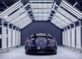 A dark blue Porsche 911 is parked under bright, evenly spaced LED lights in a modern indoor automotive facility, showcasing Porsche Italia’s dedication to design and performance.