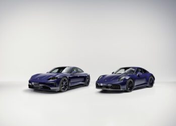Two dark blue Porsche sports cars, evoking the luxury of Porsche Italia, are parked side by side in a minimal, well-lit studio with a light gray background.