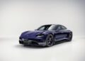 A dark blue Porsche Taycan electric sports car is displayed in a clean, bright studio setting with a plain background, embodying the refined style and innovation of Porsche Italia.