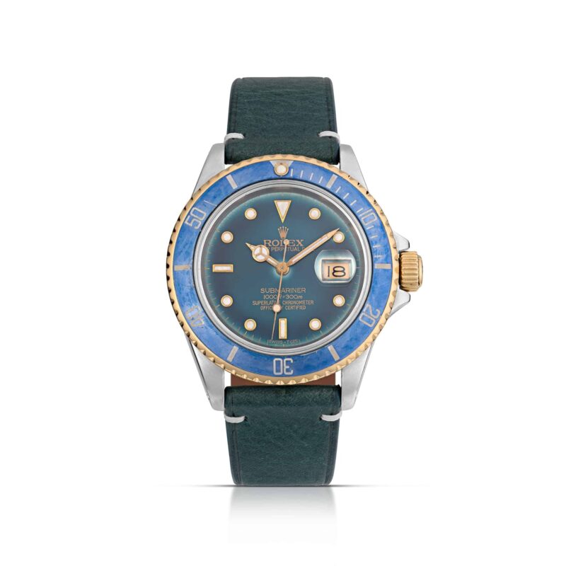 A Rolex Submariner, one of the best luxury watches, featuring a blue bezel, blue dial, gold accents, and a dark green leather strap displayed face up.
