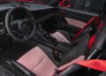 Interior of a Porsche 911 GT3 RS, featuring the iconic badge on the steering wheel, red and white checkered seats, and red seat belts—an atmosphere reminiscent of the Porsche Experience Center.