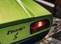 Close-up of the rear section of a Lamborghini sports car in striking Verde Scandal, with the word "Miura" and an "S" emblem near the tail light.