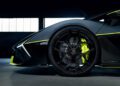 Close-up side view of a Lamborghini's front wheel and fender, featuring striking Verde Scandal neon yellow accents, parked indoors.