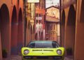 A vintage Lamborghini in Verde Scandal is parked on a narrow cobblestone street lined with colorful arched buildings.