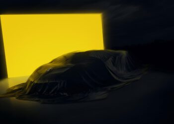 A Lamborghini Few-Off, draped in a dark cloth, stands before a large, bright yellow illuminated rectangle in a dimly lit setting—evoking the exclusive atmosphere of Monterey Car Week.