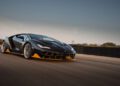A black Lamborghini Few-Off Legacy with yellow accents speeds along the racetrack at Monterey Car Week, set against a blurred background and clear sky.