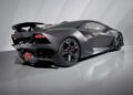 Matte black Lamborghini sports car with angular design, rear spoiler, and red accents, parked indoors on a smooth, light-colored floor—an eye-catching presence reminiscent of Monterey Car Week exclusives.