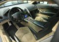 View of a luxury sports car interior featuring beige and black leather seats, a digital dashboard, central controls, and "Reventón" branding on the passenger side—an exclusive Lamborghini Few-Off model showcased at Monterey Car Week.