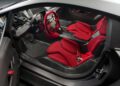 The interior of a Few-Off Lamborghini sports car featuring red bucket seats, a minimalist dashboard, and a red racing-style steering wheel, reminiscent of models showcased at Monterey Car Week.
