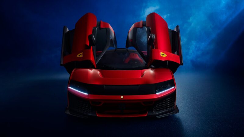 A red Ferrari F80 hypercar with both scissor doors open, viewed from the front against a blue background.