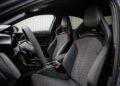 Interior view of a modern car showing the front seats with hexagonal stitching, a flat-bottom steering wheel, and sporty RS branding on the seatbacks.