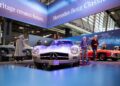 A silver classic Mercedes-Benz car on display at an indoor Rétromobile NY auto show in Manhattan, exuding European elegance as people observe and other vintage cars grace the background.