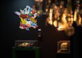 A wall decorated with a France-shaped collage, two model vehicles in display cases below, and chandelier lights in the foreground captures Manhattan’s European elegance—echoing the spirit of Rétromobile NY.
