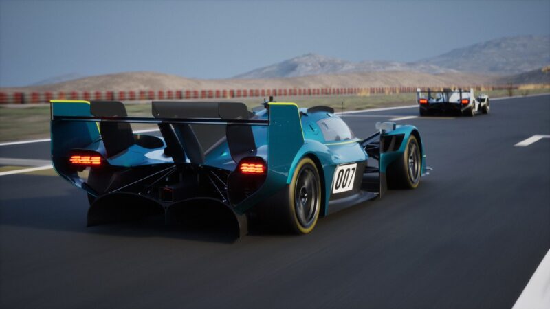 Two race cars speed along a paved track against a mountainous backdrop. The nearest, a teal 007, recalls the exclusivity of the track-only Valkyrie LM—Aston Martin’s latest hypercar infused with legendary Le Mans DNA.