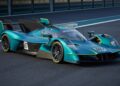 A teal, track-only Valkyrie LM, limited to 10 units and bearing the number 007, sits on a racetrack. This Aston Martin hypercar boasts Le Mans DNA, aerodynamic bodywork, yellow accents, and a large rear wing.