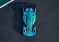 A teal and black Aston Martin track-only Valkyrie LM, seen from above, sits on dark asphalt near a green and white track edge, with the number 007 on the front—Aston Martin’s latest hypercar infused with Le Mans DNA.