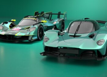 Two teal Aston Martin hypercars, including the Valkyrie AMR LMH set to make its Le Mans debut, are showcased side by side—one in race-ready form with sponsor decals and the other in a sleek road car version.