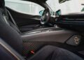Interior view of the Pininfarina Battista reveals black leather seats, carbon fiber accents, and a detailed dashboard with modern controls—exemplifying the luxury and innovation found in the last Battista models.
