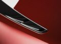 Close-up of a shiny red Pininfarina Battista surface with chrome and black detailing, reflecting light and highlighting smooth curves.