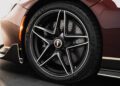 Close-up of a black and silver alloy wheel with a Michelin tire on the Pininfarina Battista, showcasing its ventilated disc brake behind the rim on this stunning maroon hypercar.