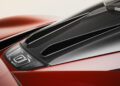 Close-up of the Pininfarina Battista's rear engine cover with black air vents and red body panels, highlighting part of a tail light and striking aerodynamic design features.