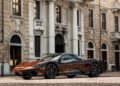 A Pininfarina Battista luxury sports car is parked on a cobblestone street in front of the NH Collection Piazza Carlina hotel, a historic stone building with large windows and balconies.