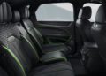 The image shows the interior of a Bentley Bentayga Speed, with black leather seats, green trim accents, and detailed stitching, featuring rear seat controls and spacious legroom in the most powerful Bentayga.
