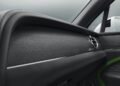 Close-up view of a new Bentayga's interior door panel, featuring black leather, wood trim, a green accent, and a circular air vent—showcasing the luxury of the powerful Bentayga.
