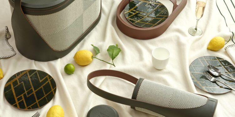 Picnic setup featuring the Hyde Picnic Collection from Bentley Home: modern baskets, lemons, geometric plates, a glass of champagne, cup, and key—all beautifully arranged for elevated outdoor living on a light-colored blanket.
