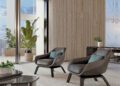 Two modern armchairs with cushions face each other in a bright, minimalist room with tall windows, indoor plants, and a small table—capturing the luxe ambiance of a $37.5M Bentley Residences Miami penthouse.