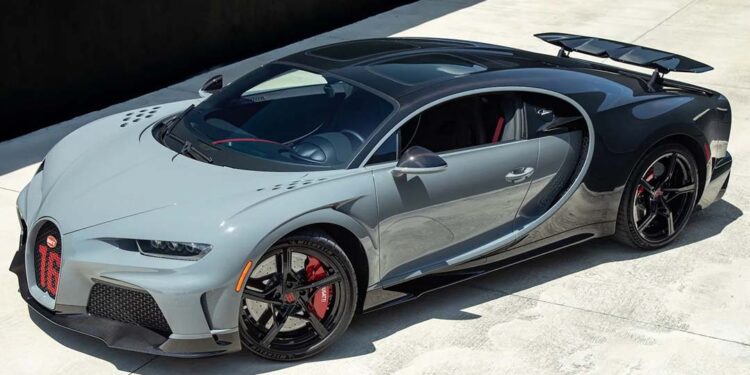 A grey Bugatti Chiron hypercar is parked on a concrete surface in bright daylight.