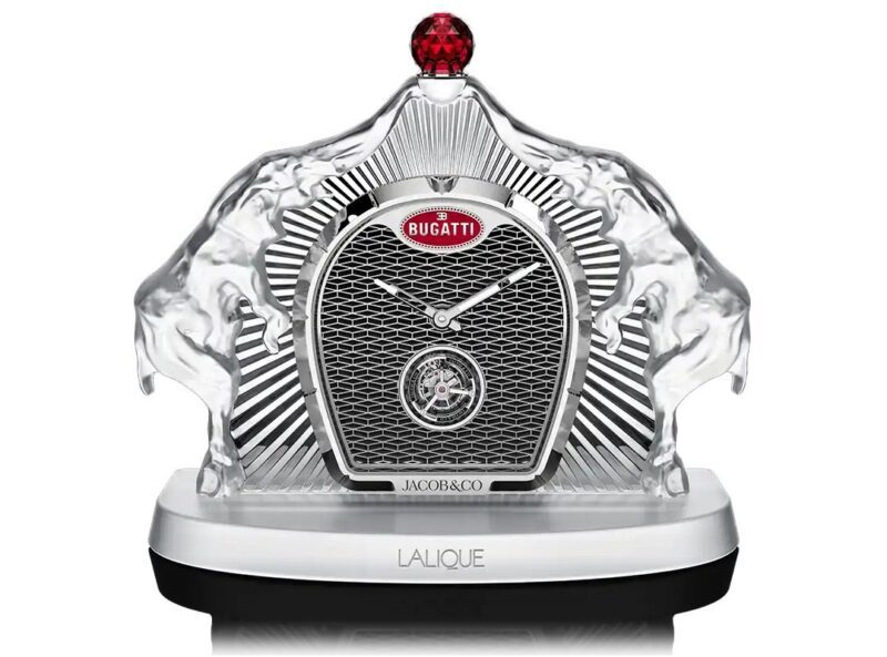 A luxury table clock featuring the Bugatti Calandre Table Clock grille design, clear sculpted elements, and branding from Jacob & Co., Lalique, and Bugatti, set on a sleek base.