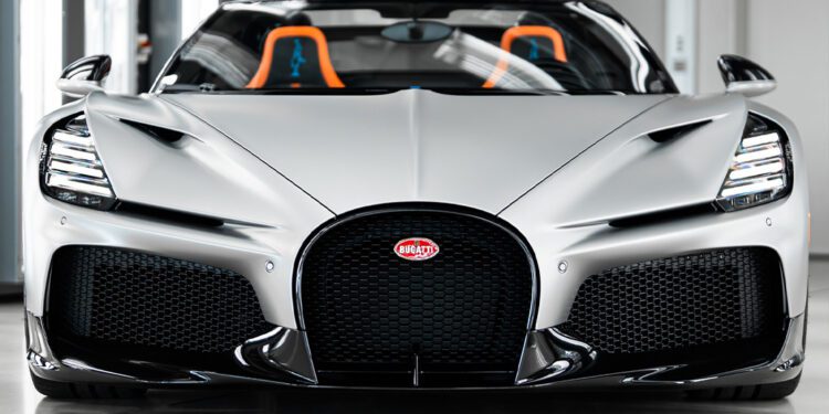 Front view of a silver $5M Bugatti Mistral with black grille and orange-accented seats, parked indoors—captured by Matt Argent.