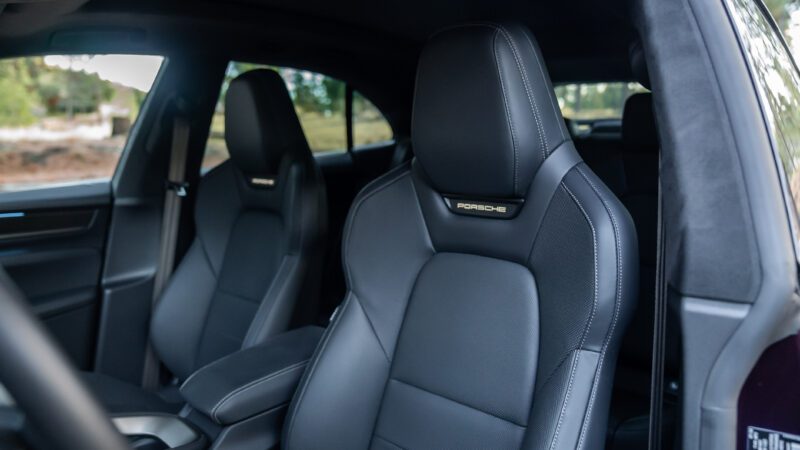 Close-up view of the front black leather seats inside a modern Porsche vehicle, with a "Porsche" logo visible on the headrest.