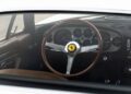 View through the window of a Euro-Spec 365 GTB/4, showing a wooden steering wheel with Ferrari logo, analog gauges, and vintage dashboard controls—a timeless interior reminiscent of Ferrari Beverly Hills sophistication.
