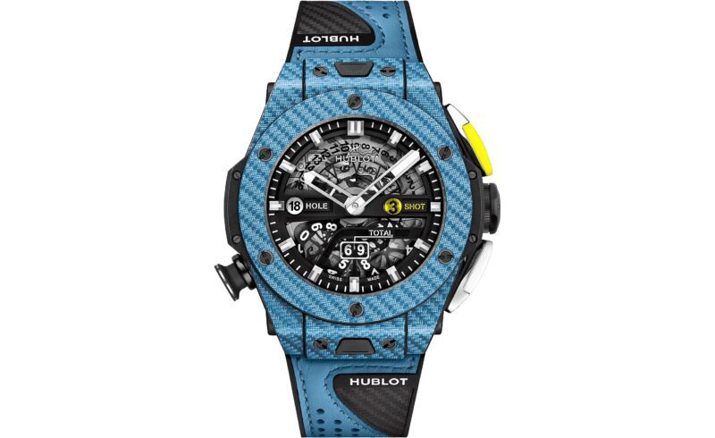 A Hublot wristwatch with a blue bezel, black perforated strap, and a skeleton dial displaying various counters and yellow detail on the right side button—an outstanding pick among the best luxury watches.