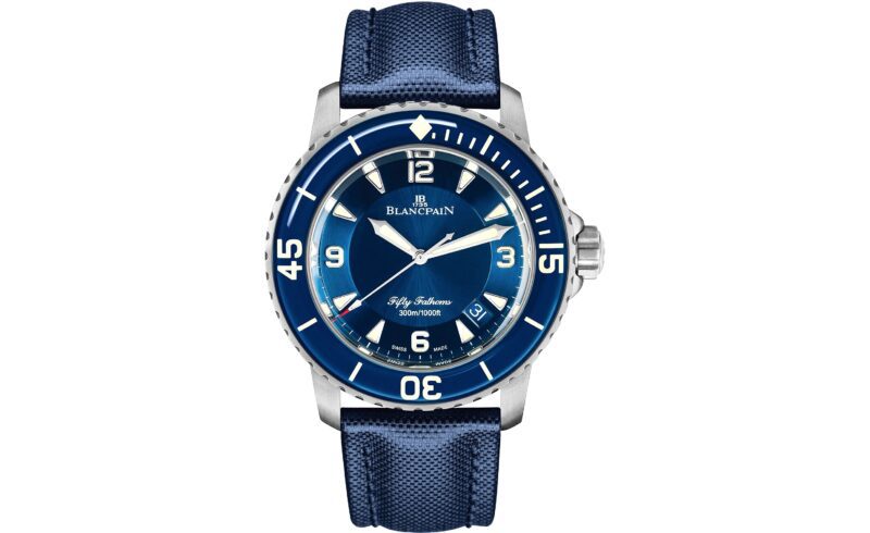 A blue Blancpain Fifty Fathoms dive watch with a blue dial, white markers, date window at 4 o’clock, and blue strap stands out among the best luxury watches. The bezel has large numerals and the case is stainless steel.