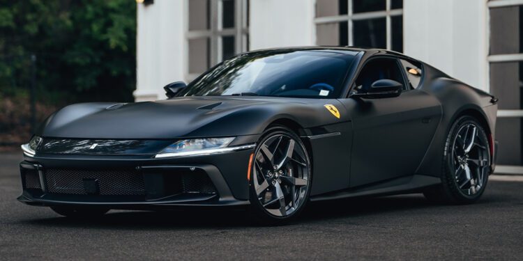 A matte black Ferrari 12Cilindri, boasting 819HP, is parked in front of a white building with large windows and exterior lights—a stunning showcase from Miller Motorcars.