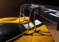 Close-up of a large carbon fiber rear wing mounted on a yellow Ferrari 296 GT3 Evo, with visible aerodynamic supports and GT3 lettering, captured during the 24 Hours Of Spa.