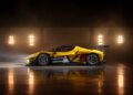A yellow and black Ferrari 296 GT3 Evo race car with a rear wing is parked indoors on a reflective floor, bright lights illuminating the background, ready for the thrill of the 24 Hours Of Spa.