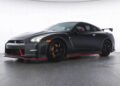 A matte black Nissan GT-R JDM sports car with red accents and a rear spoiler is parked in a studio setting.