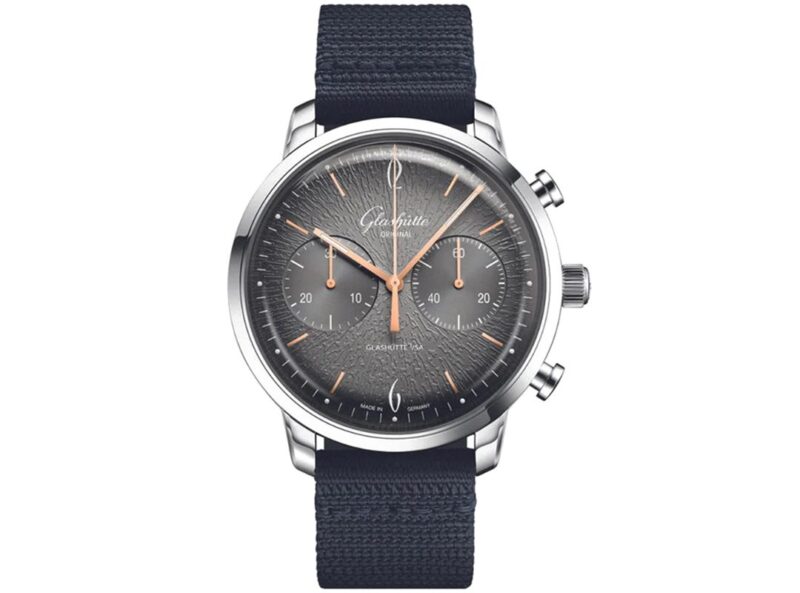 Featured in the duPont REGISTRY Gift Guide, this silver chronograph wristwatch boasts a textured gray dial, rose gold hands, two sub-dials, and a black fabric strap—an exceptional choice for Father’s Day.