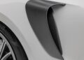 Close-up of Gunther Werks Goes Modern: Meet GW9’s Carbon-Clad 992 Turbo S, showcasing its carbon fiber air vent on a white body, with part of a wheel and tire visible on the left side.