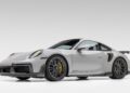 A white Porsche 911 Turbo S sports car is shown in a studio with a plain background, featuring black rims and yellow brake calipers—Gunther Werks Goes Modern: Meet GW9’s Carbon-Clad 992 Turbo S.