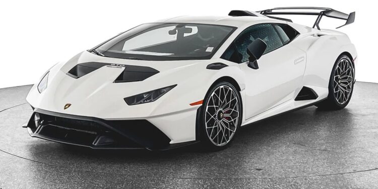 A white Lamborghini Huracan STO, the ultimate Italian track star with black accents and a rear wing, parked on a gray surface against a white background. For sale now.